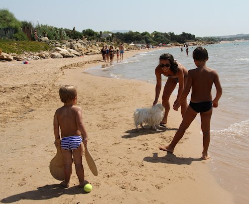 Mutter mit zwei Kindern und Hund auf Sardinien am Strand.